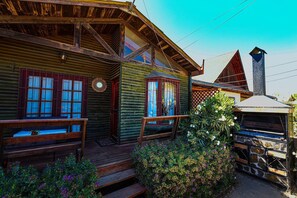 Une cabane rustique en rondins de bois, dotĂ©e dâun porche, de bancs en bois et dâune cheminĂ©e en pierre.