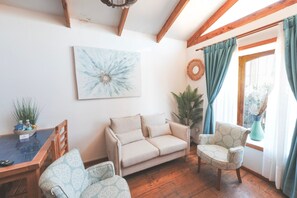 Un salon comprenant un canapé, deux fauteuils à motifs, une table basse et une table à manger.