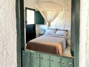 A bedroom with a bed, a hanging light fixture, and a window. - Cortijo with eclectic décor near Almería (Albaricoques)