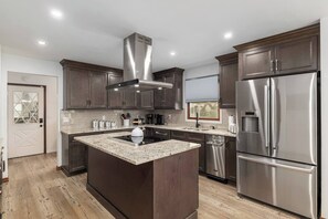 A modern kitchen with dark wood cabinets, stainless steel appliances, and a central island. - Horsey Heartland oasis 7 Mi WEC Close to all Fun (Ocala)