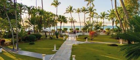 A pathway leading to a beach with palm trees and a view of the ocean.