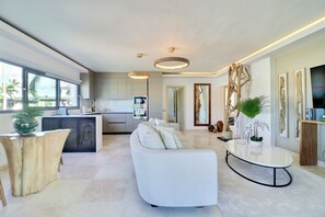 Ein modernes Wohnzimmer mit einem weißen Sofa, einem Couchtisch und einer Küche im Hintergrund.
