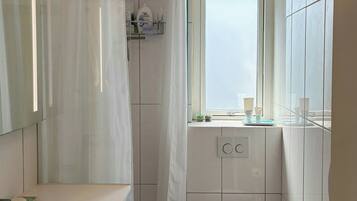 A bathroom with a shower, toilet, sink, and a window.