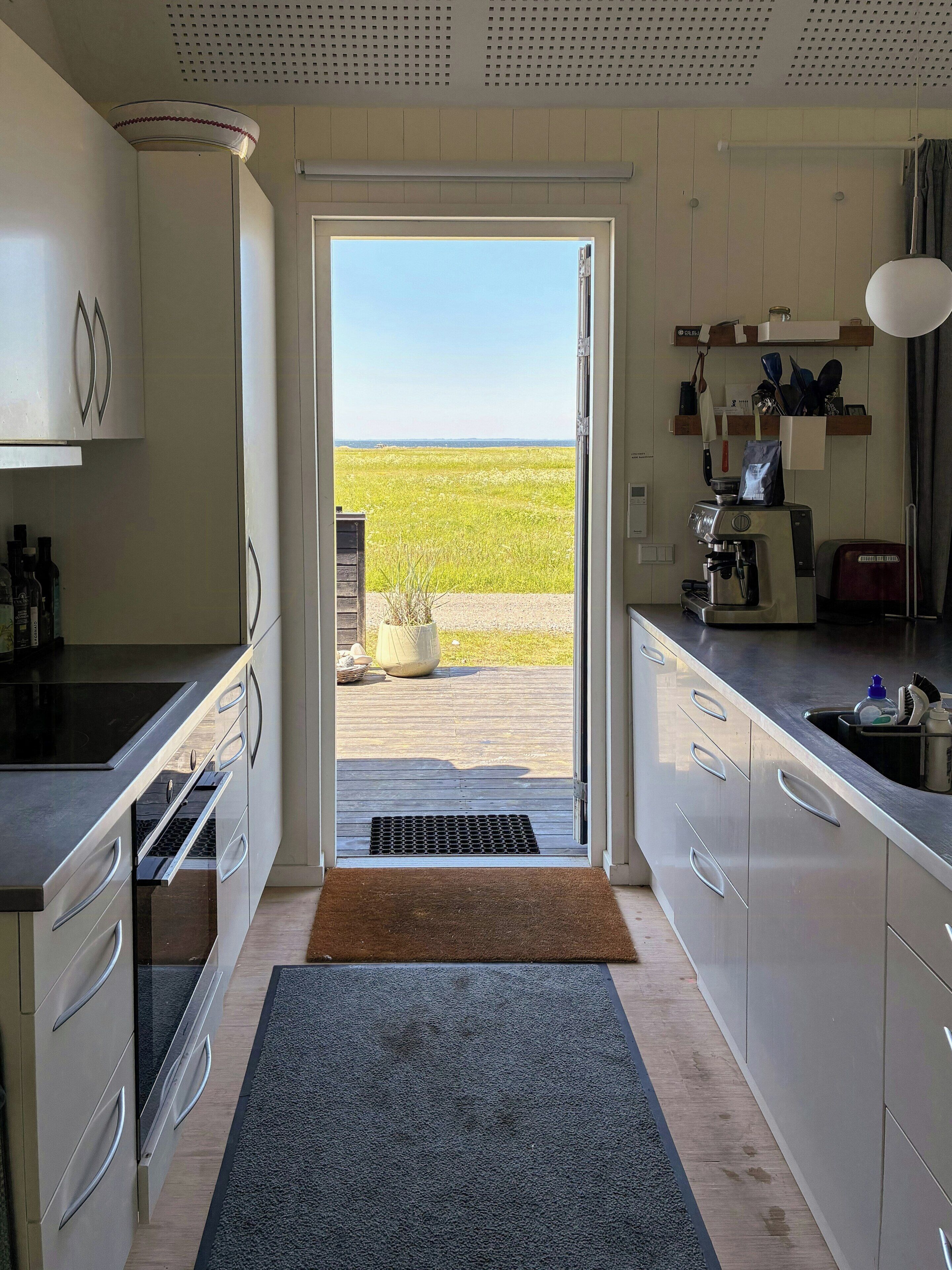 A modern kitchen with a view of a field, a coffee machine, and a toaster.. Fjord Views and a Child‑Friendly Beach in Lendrup