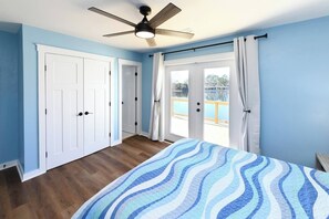 Ein Schlafzimmer mit Bett, Deckenventilator und Seeblick durch eine Glastür.