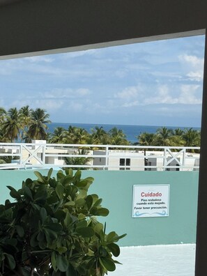 Blick auf einen Poolbereich, mit einem Schild, das vor rutschigen Böcken bei Nässe warnt.