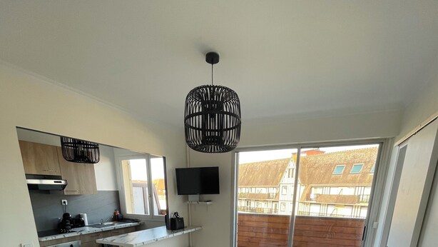 Um apartamento moderno com cozinha, sala de jantar e um sofá grande com pufes.