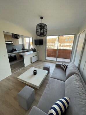 Un appartement moderne comprenant une cuisine, un coin repas et un grand canapé avec des poufs.