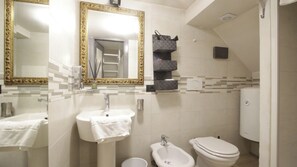 Casa de banho com lavatório, espelho, sanita e zona de duche.