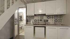 A compact kitchen with white cabinets, a small refrigerator, and a patterned backsplash. - Coppelle Nights at the Pantheon (Roma)