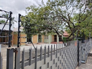 A gated area with a metal fence, trees, and buildings in the background. - Laroza Guest House (Rustenburg)
