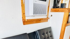 Ein schwarzes Ledersofa mit Holzrahmen, ein kleiner Tisch und eine weiße Wandklimaanlage.