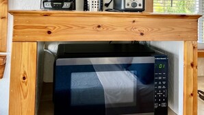 Eine Küche mit Kaffeemaschine, Toaster und Mikrowelle auf einem Holzboden.