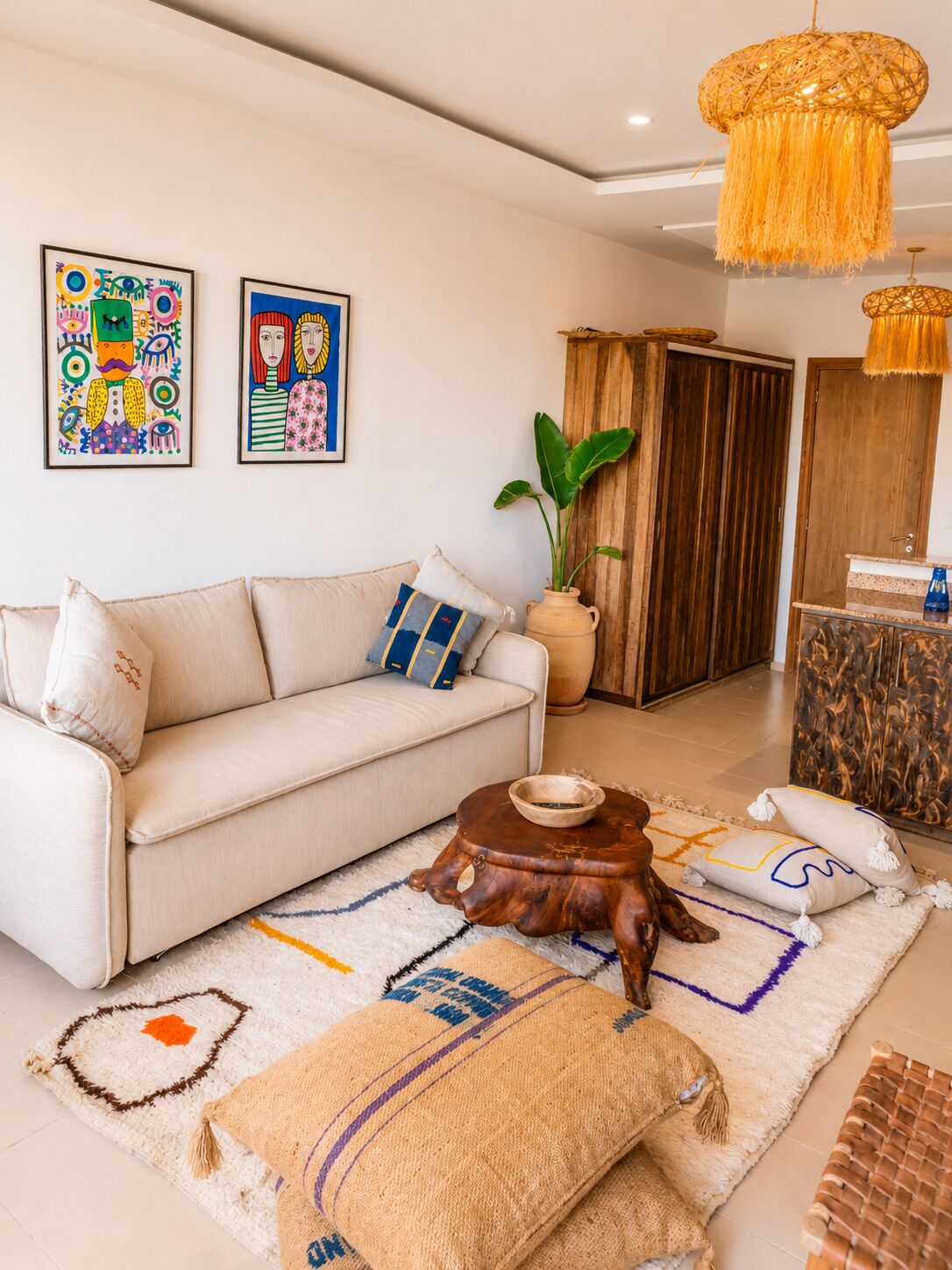 Un salon comprenant un canapé, une table basse, un tapis et deux œuvres d’art accrochées au mur.