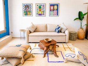A living room with a sofa, a coffee table, and three framed artworks on the wall. - Panoramic Ocean View Apartment (Essaouira)