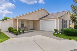 Einbungalow mit Garage, überdachter Terrasse und kleinem Rasen.