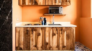 Une cuisine avec des meubles de rangement en bois, un four à micro-ondes, une machine à café et un évier.