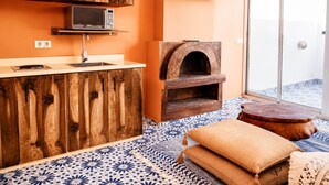 Une cuisine avec des meubles en bois, un four à micro-ondes, une télévision et un four à pizza.