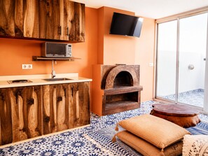 A kitchen with wooden cabinets, a microwave, a television, and a pizza oven. - Ocean View Studio in Essaouira (Essaouira)