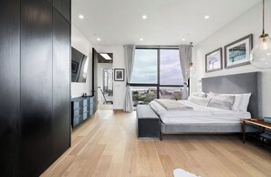 Ein modernes Schlafzimmer mit einem großen Bett, einem Nachttisch, einem Kleiderschrank und Blick auf die Stadt.