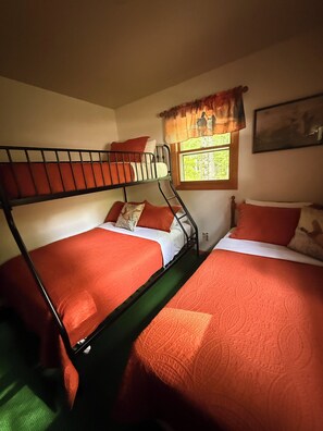 Une chambre avec des lits superposés, une fenêtre donnant sur un beau paysage et un tableau accroché au mur.