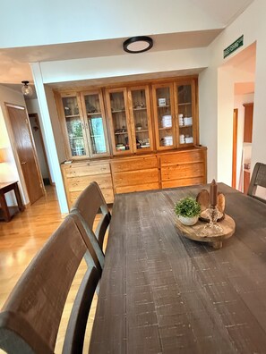 Un coin repas comprenant une table en bois, des chaises et un buffet aux portes vitrées.