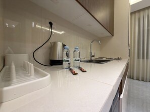 A modern kitchen with a sink, kettle, and water bottles on the counter. - 104 JRE Apartment With Stunning Boulevar (Amman)