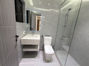 A modern bathroom with a glass shower enclosure, a white sink, and a toilet. - 104 JRE Apartment With Stunning Boulevar (Amman)