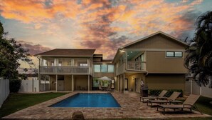 Uma casa de dois andares com piscina, área de estar externa e varanda.