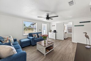 Ein Wohnzimmer mit einem blauen Sofa, einem Couchtisch und einem Deckenventilator.