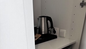 A kitchen with a white countertop, a stainless steel kettle, and a black electric kettle. - Athens Stay 15 Hotel-Style Room & King Bed (Athina)