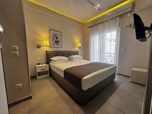 A modern hotel room with a large bed, bedside lamps, a small table, and a view of the outdoors.