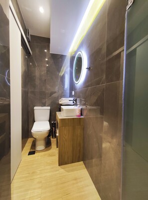 Ein modernes Badezimmer mit Toilette, Waschtisch und Duschbereich.