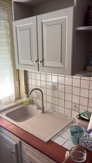 A kitchen with white cabinets, a sink, and a tiled backsplash. - Sea Breeze House for 4 people, 5 minutes from the beach (Fiumenaro)