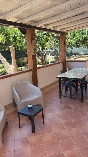 An outdoor patio with a table and chairs, a small table with a bottle, and a brick wall. - Sea Breeze House for 4 people, 5 minutes from the beach (Fiumenaro)