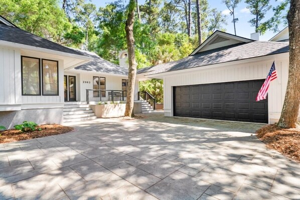 A two-story house with a garage, a front porch, and a driveway. - Seabrook Exclusives | 2963 Seabrook Island Rd (Seabrook Island)