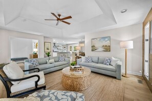 A modern living room with a ceiling fan, two grey sofas, a coffee table, and a floor lamp. - Seabrook Exclusives | 2963 Seabrook Island Rd (Seabrook Island)