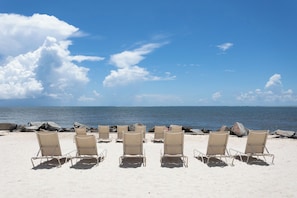 A beach with rows of beige lounge chairs facing the ocean. - Seabrook Exclusives | 2963 Seabrook Island Rd (Seabrook Island)