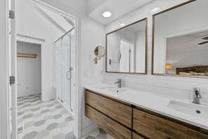 A modern bathroom with a glass shower door, two sinks, wooden vanity, and large mirrors. - Seabrook Exclusives | 2963 Seabrook Island Rd (Seabrook Island)