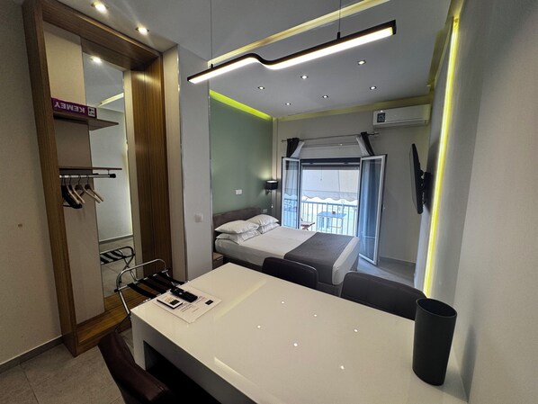 A modern hotel room with a bed, a desk, a chair, a wardrobe, and a balcony with a table and chairs. - Athens Stay 35 (Athina)