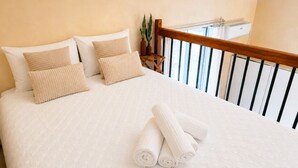 A neatly made bed with rolled towels, a wooden headboard, and a potted plant. - Duomo 31 Loft · Catania Centre Balcony & Cathedral (Catania)