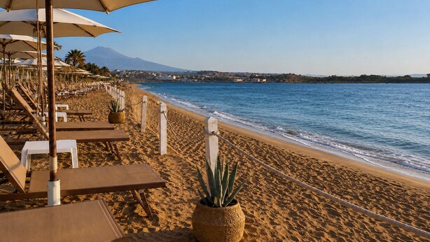 A beach with sun loungers and umbrellas, a sandy shore, and a view of a mountain in the distance. - Duomo 31 Loft · Catania Centre Balcony & Cathedral (Catania)