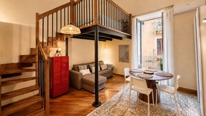 A modern interior with a wooden staircase, a red refrigerator, a sofa, a dining table with chairs, and a patterned rug. - Duomo 31 Loft · Catania Centre Balcony & Cathedral (Catania)