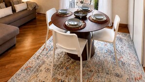 A dining area with a round table set for four, a sofa, a patterned rug, and a staircase. - Duomo 31 Loft · Catania Centre Balcony & Cathedral (Catania)