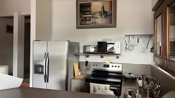 Cozinha equipada com geladeira, micro-ondas, fogão e um porta-utensílios suspenso.