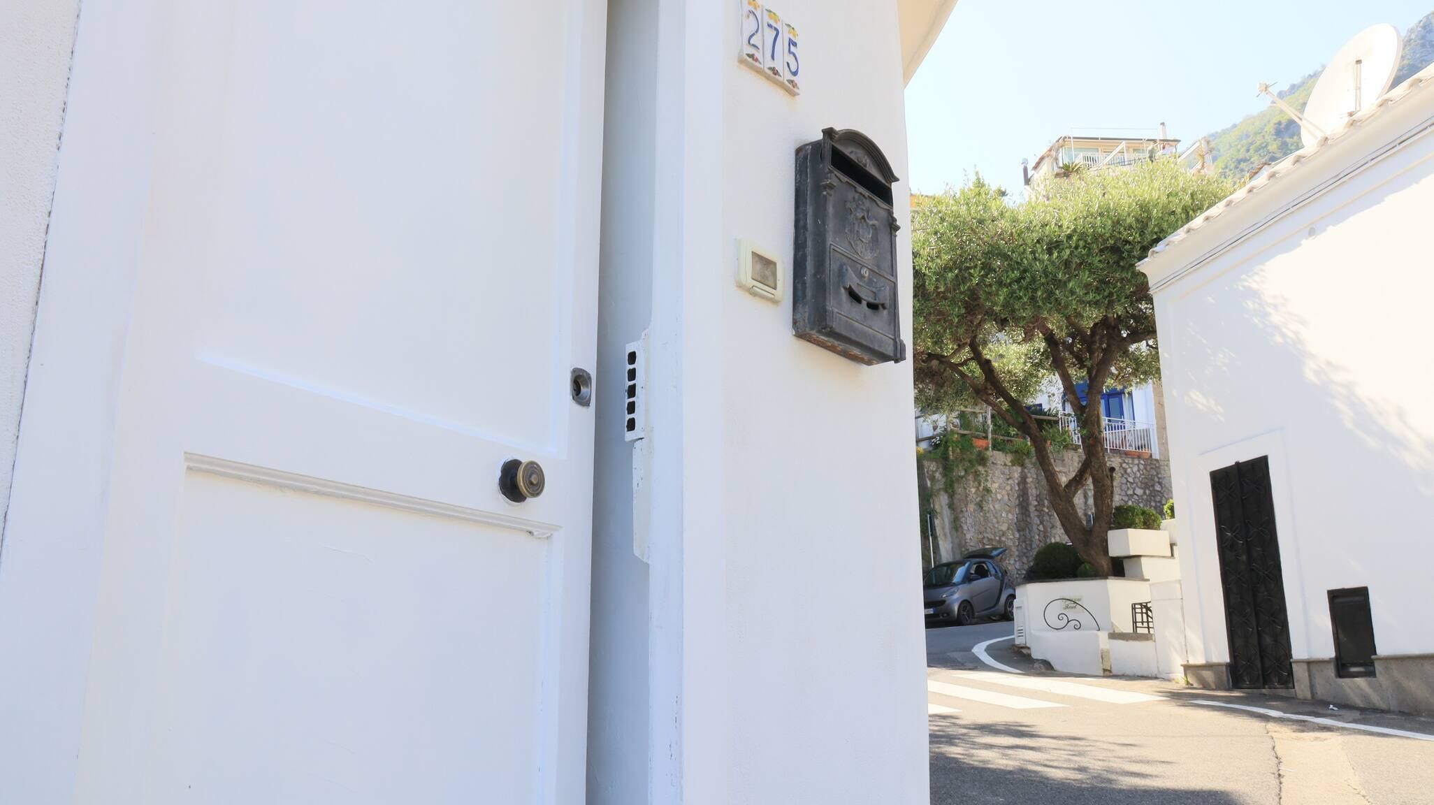 A white building with a door, a mailbox, and a tree in the background.