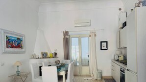 Ein kompakter Wohnraum mit Essbereich, Küchenzeile und einem Balkon mit Vorhängen.