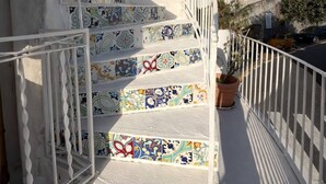 Eine Treppe mit bunten Fliesen führt zu einem Balkon mit einer weißen Brüstung.