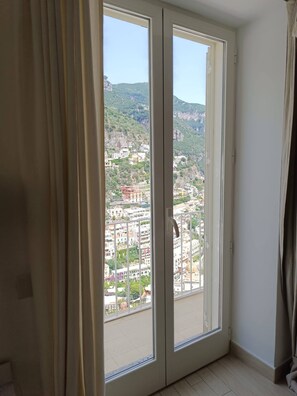 A room with a large sliding glass door leading to a balcony with a city view. - Luxury Panoramic Villa Positano- sea View (Positano)