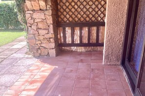 Eine Terrasse mit Steinmauern, einem Holzzaun und einem gefliesten Boden.
